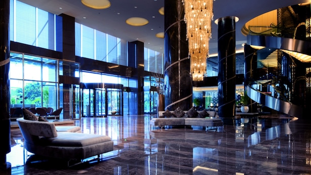 Un hall d’entrée spacieux agrémenté d’un lustre moderne, d’un coin salon avec des canapés et d’un escalier.