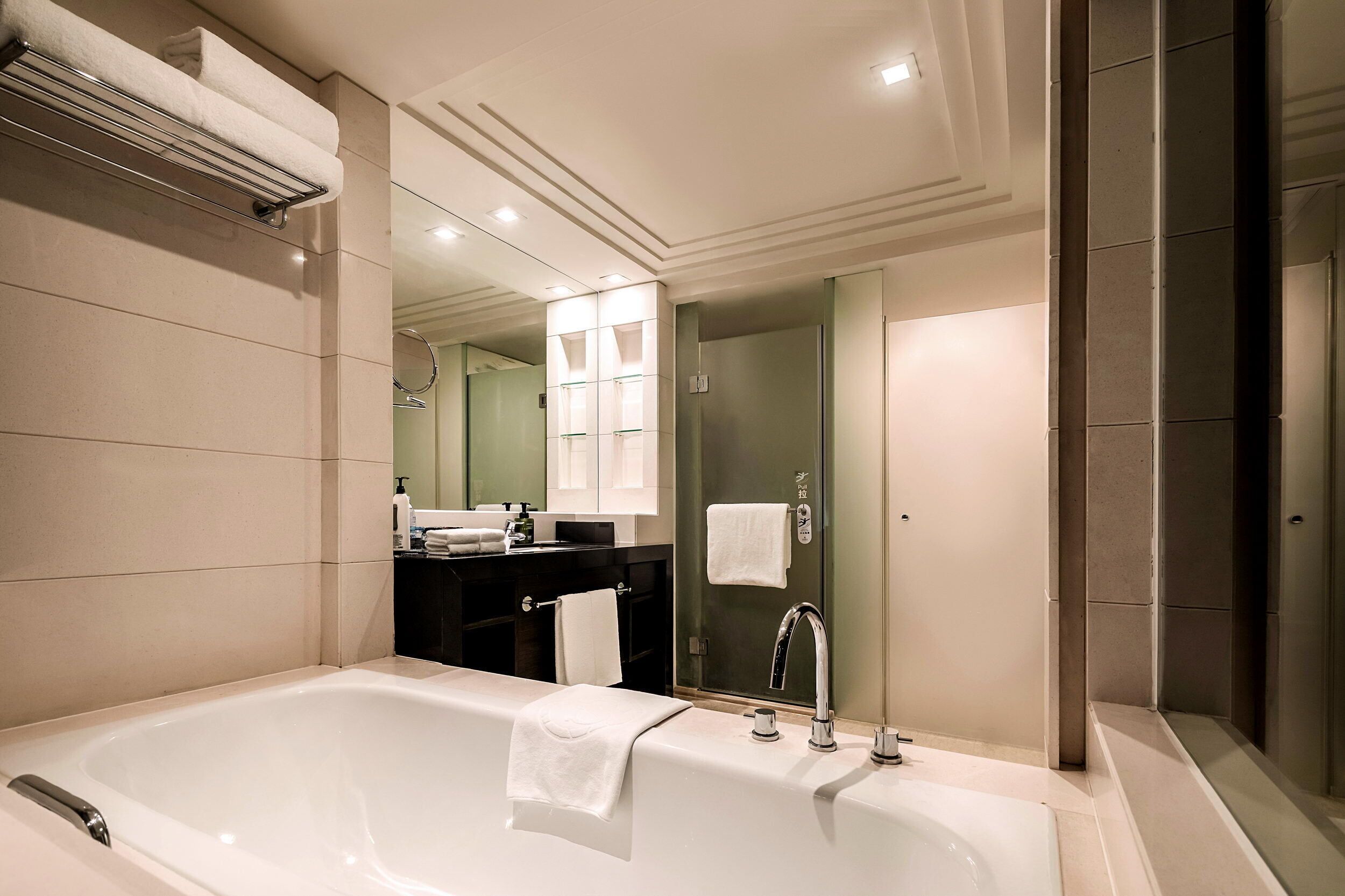 Une salle de bain moderne avec une grande baignoire, un meuble-lavabo avec un miroir et une cabine de douche en verre.