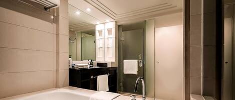 Une salle de bain moderne avec une grande baignoire, un meuble-lavabo avec un miroir et une cabine de douche en verre.