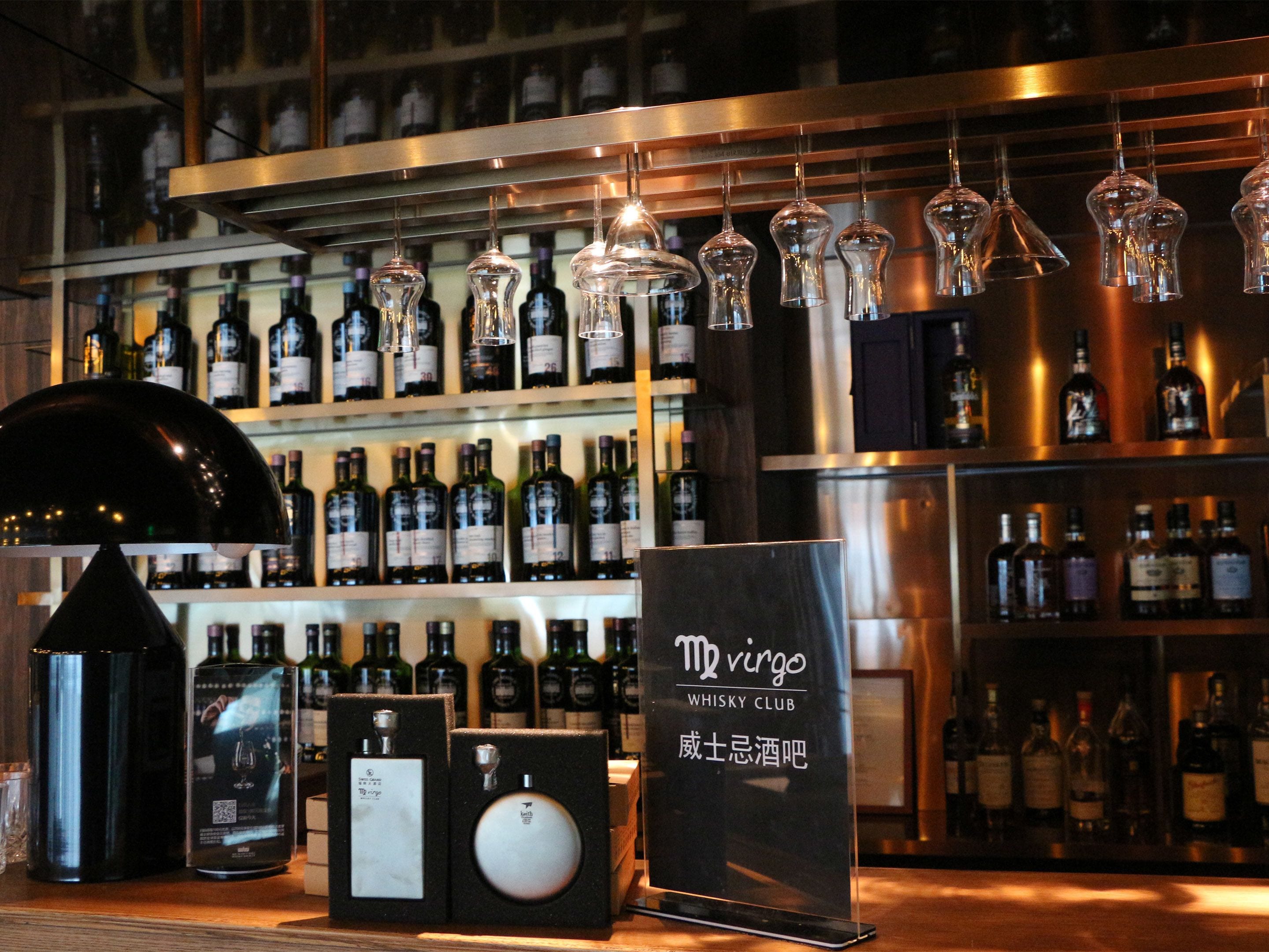 A bar area with shelves of wine bottles, a whiskey display, and hanging light fixtures.
