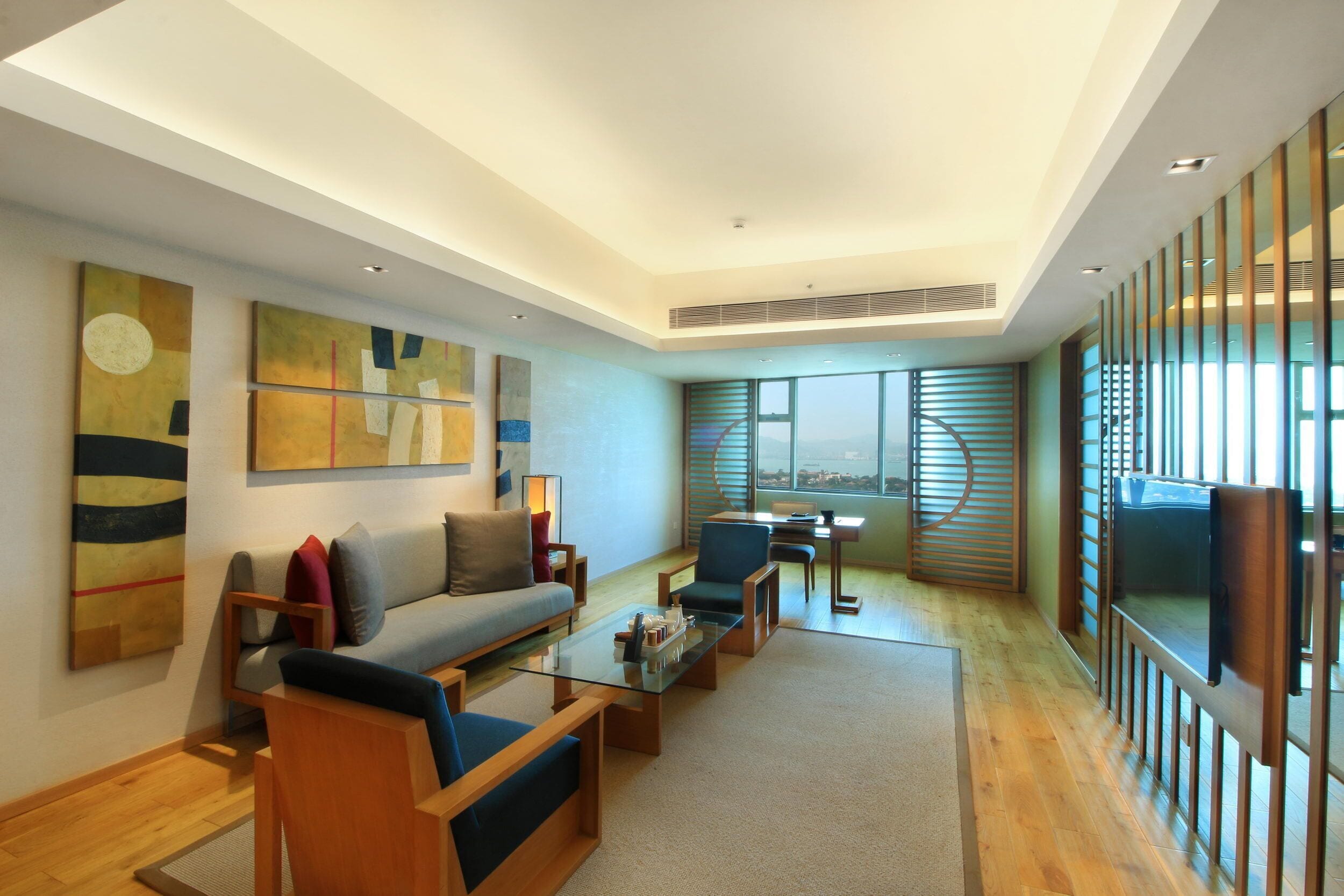 A modern living room with a sofa, armchairs, a coffee table, and artwork on the walls.