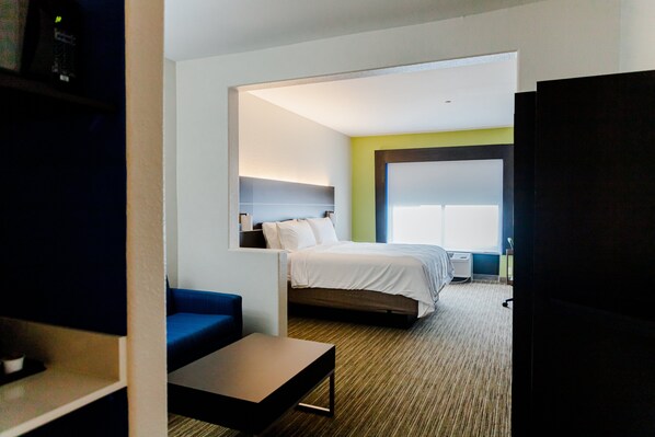 A modern hotel room with a bed, a blue sofa, a small table, and a large window. - Holiday Inn Express Andalusia by IHG (Andalusia)