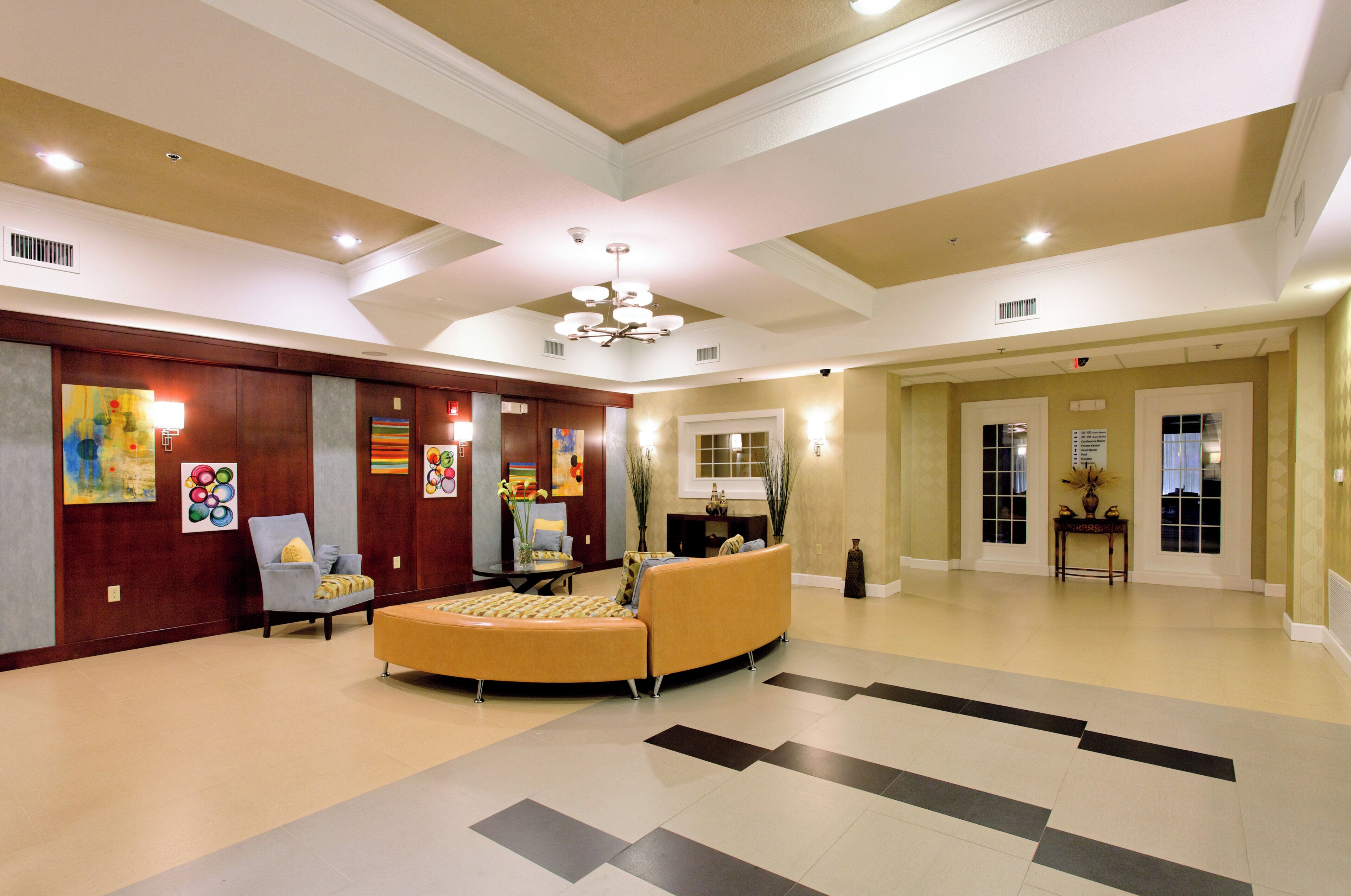 Un hall d’entrée spacieux, doté d’un espace salon aux lignes courbes, d’œuvres d’art accrochées aux murs et d’un plafond pourvu d’un éclairage encastré.