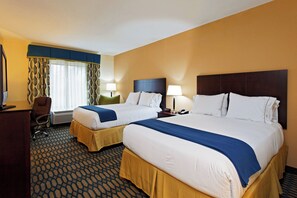 A hotel room with two beds, a desk, a chair, and a window with curtains.
