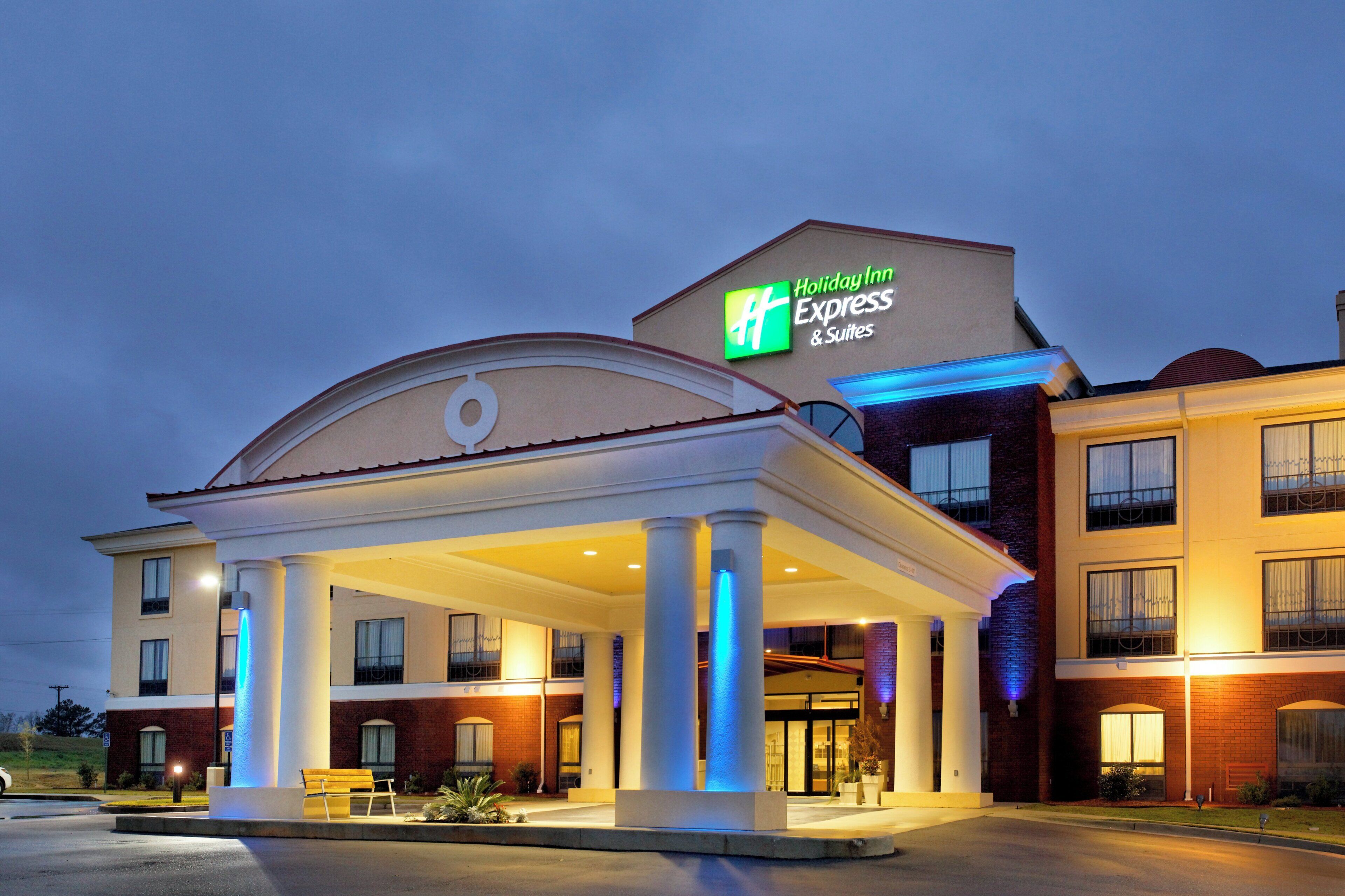 A Holiday Inn Express & Suites building with a covered outdoor area and a sign indicating the hotel name.