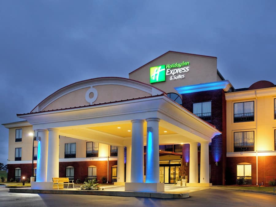 A Holiday Inn Express & Suites building with a covered outdoor area and a sign indicating the hotel name.