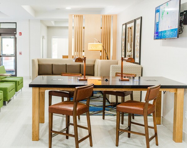 A modern hotel room with a dining area, a sofa, and a TV mounted on the wall. - Holiday Inn Express Andalusia by IHG (Andalusia)