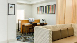 A modern office space with a desk, computer, and chairs. There is a framed certificate on the wall and a colorful striped artwork.