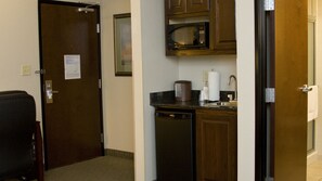 A compact kitchen with a microwave, coffee maker, and sink.
