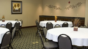 Un salón de conferencias con varias mesas y sillas, un cuadro en la pared y decoración mural.