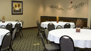 A conference room with multiple tables and chairs, a framed picture on the wall, and decorative wall art.