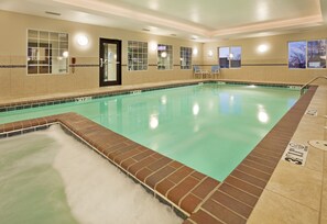 An indoor swimming pool with a clear water surface, surrounded by a tiled wall and a brick border. - Holiday Inn Express Hotel & Suites Pittsburg by IHG (Pittsburg)