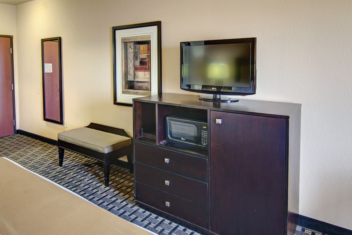 Ein Hotelzimmer mit Fernseher auf einem Schrank, einem kleinen Tisch und einem Spiegel an der Wand.