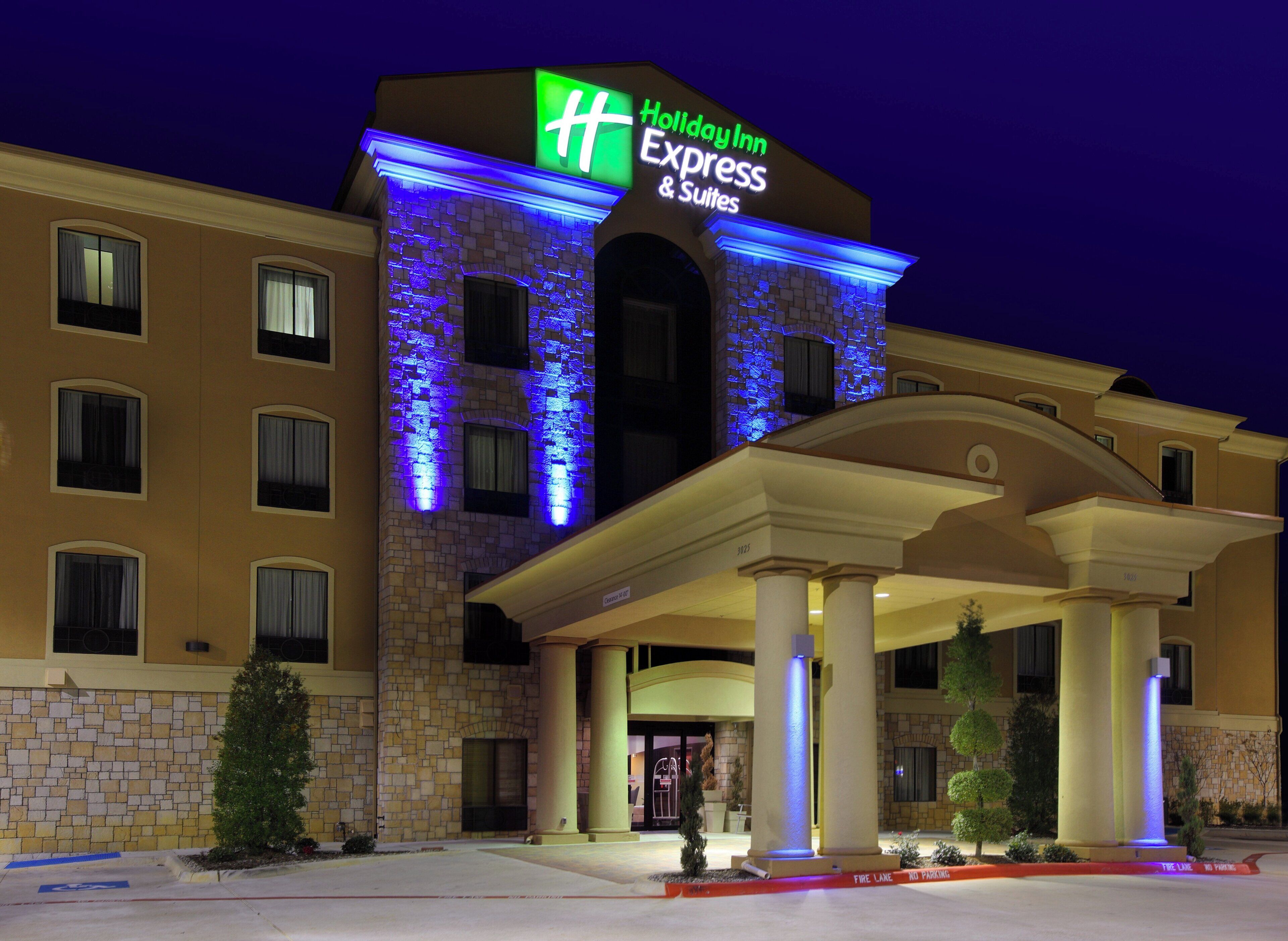 A Holiday Inn Express & Suites hotel with a stone facade and illuminated signage.