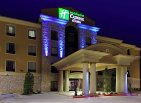 Un hotel Holiday Inn Express & Suites con fachada de piedra y señalización iluminada.