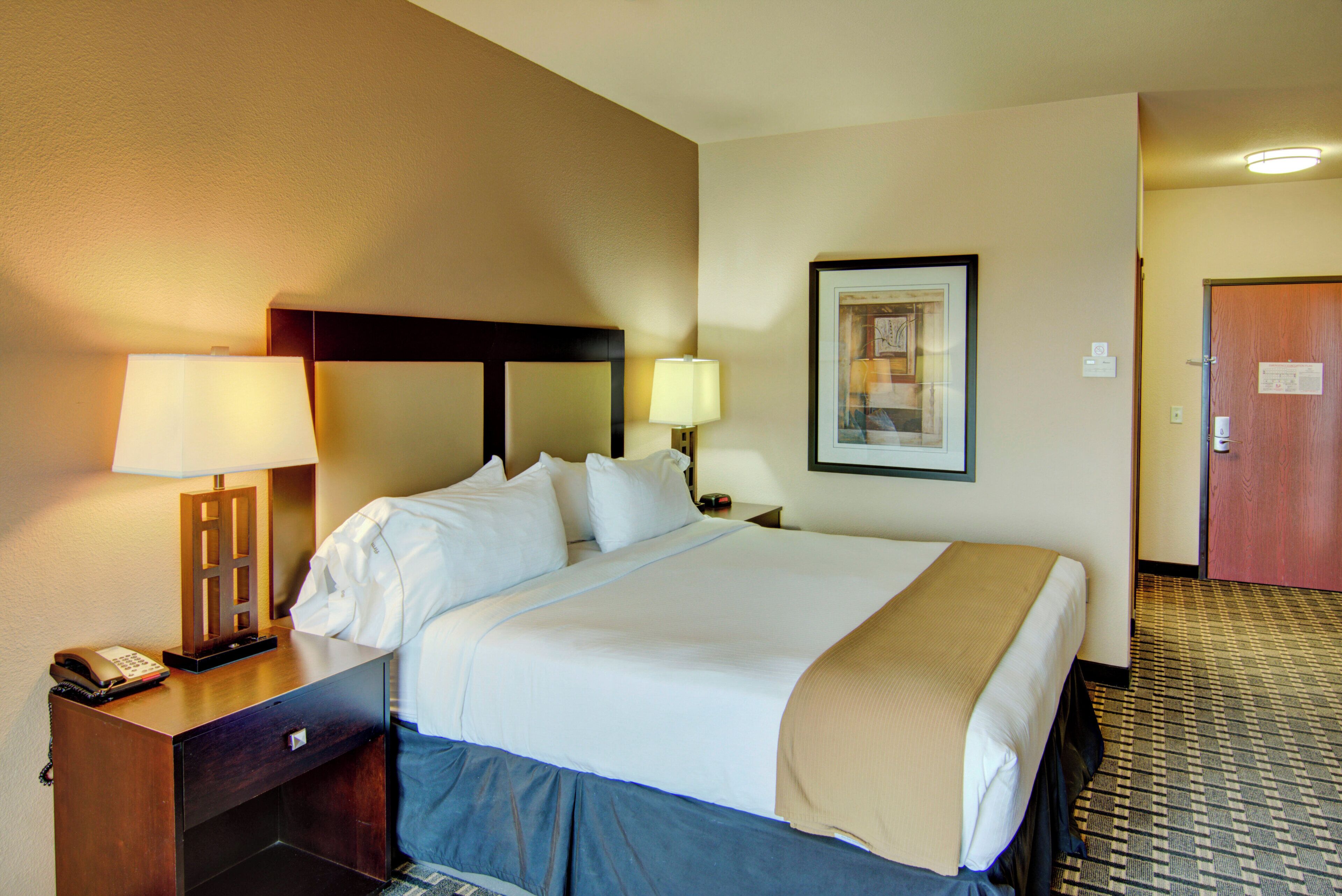 A hotel room with a bed, two bedside lamps, a telephone, and a framed picture on the wall.