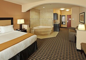 A hotel room with a large bed, a separate bathroom with a bathtub, a desk with a chair, and a patterned carpet. - Holiday Inn Express & Suites Paris, Texas by IHG (Paris)