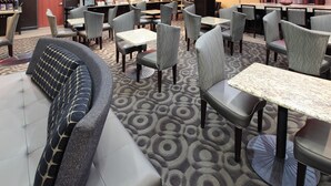 A hotel lobby with a seating area featuring sofas and tables, a reception desk, and a buffet counter.