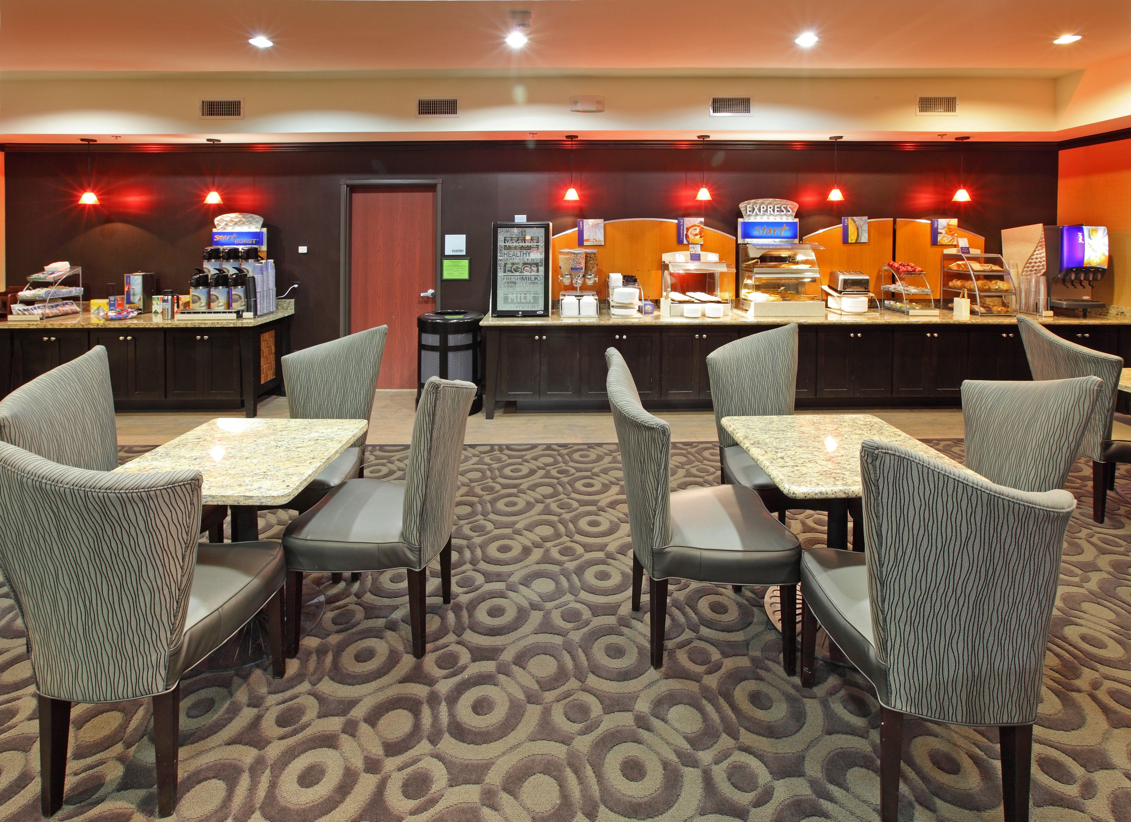 A hotel lobby with a reception desk, seating area with tables and chairs, and a coffee bar.