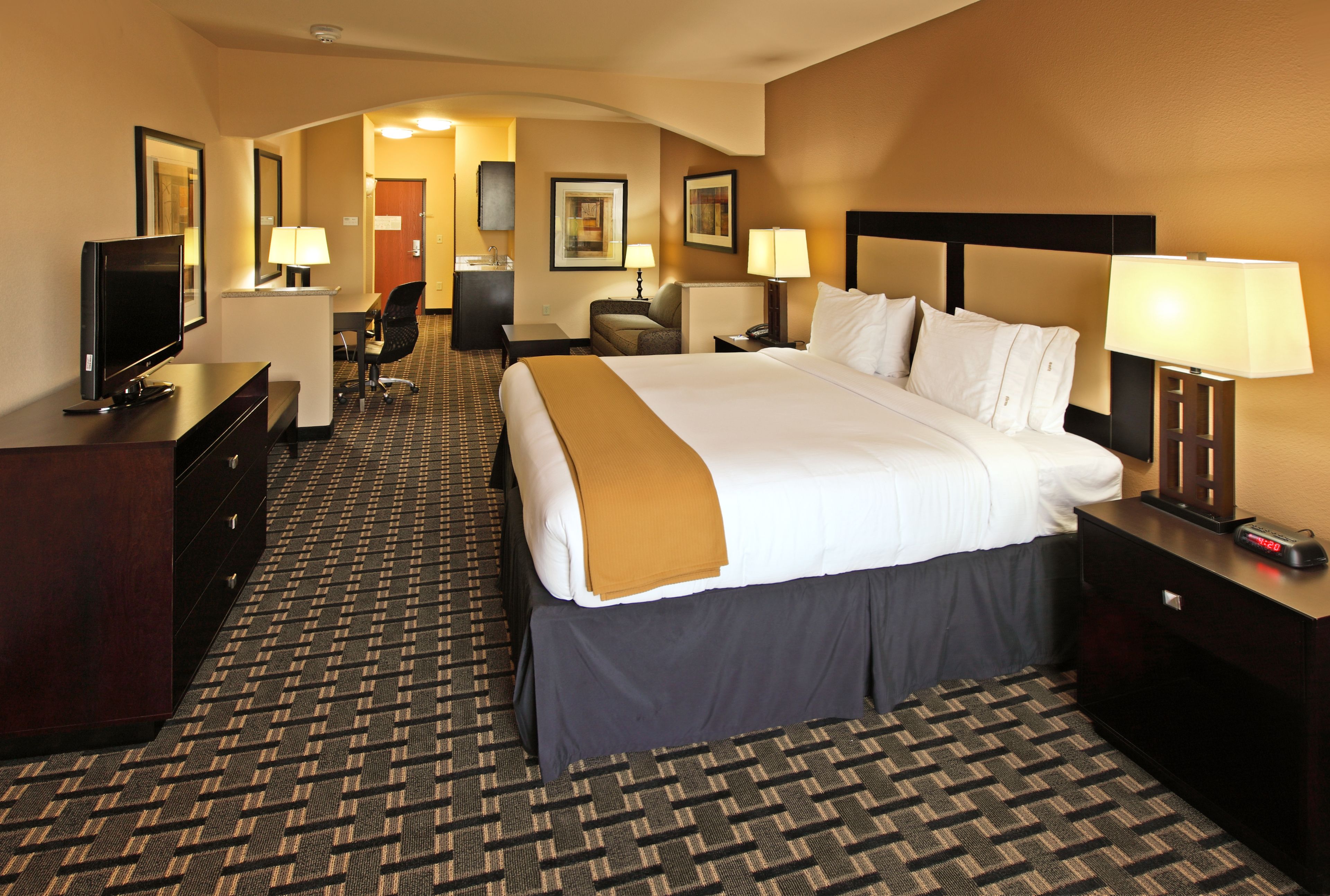 Quarto de hotel com uma cama grande, televisão, escrivaninha e uma cadeira.