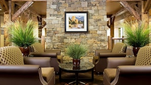 A cozy lobby with leather sofas, a stone wall, and a framed picture of a landscape. - Homewood Suites by Hilton Bozeman (Bozeman)