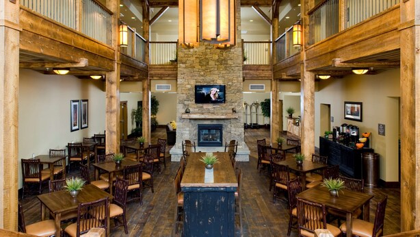 A spacious lobby with a central fireplace, wooden flooring, and multiple seating areas. - Homewood Suites by Hilton Bozeman (Bozeman)