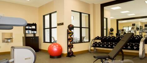 A gym with treadmills, a stationary bike, a red exercise ball, and various weights.