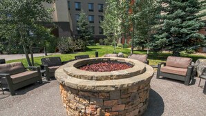 A stone fire pit surrounded by outdoor seating. - Homewood Suites by Hilton Bozeman (Bozeman)