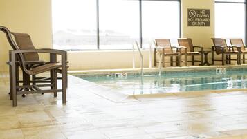 Piscina interior con sillones de descanso y letrero que prohíbe el clavado.