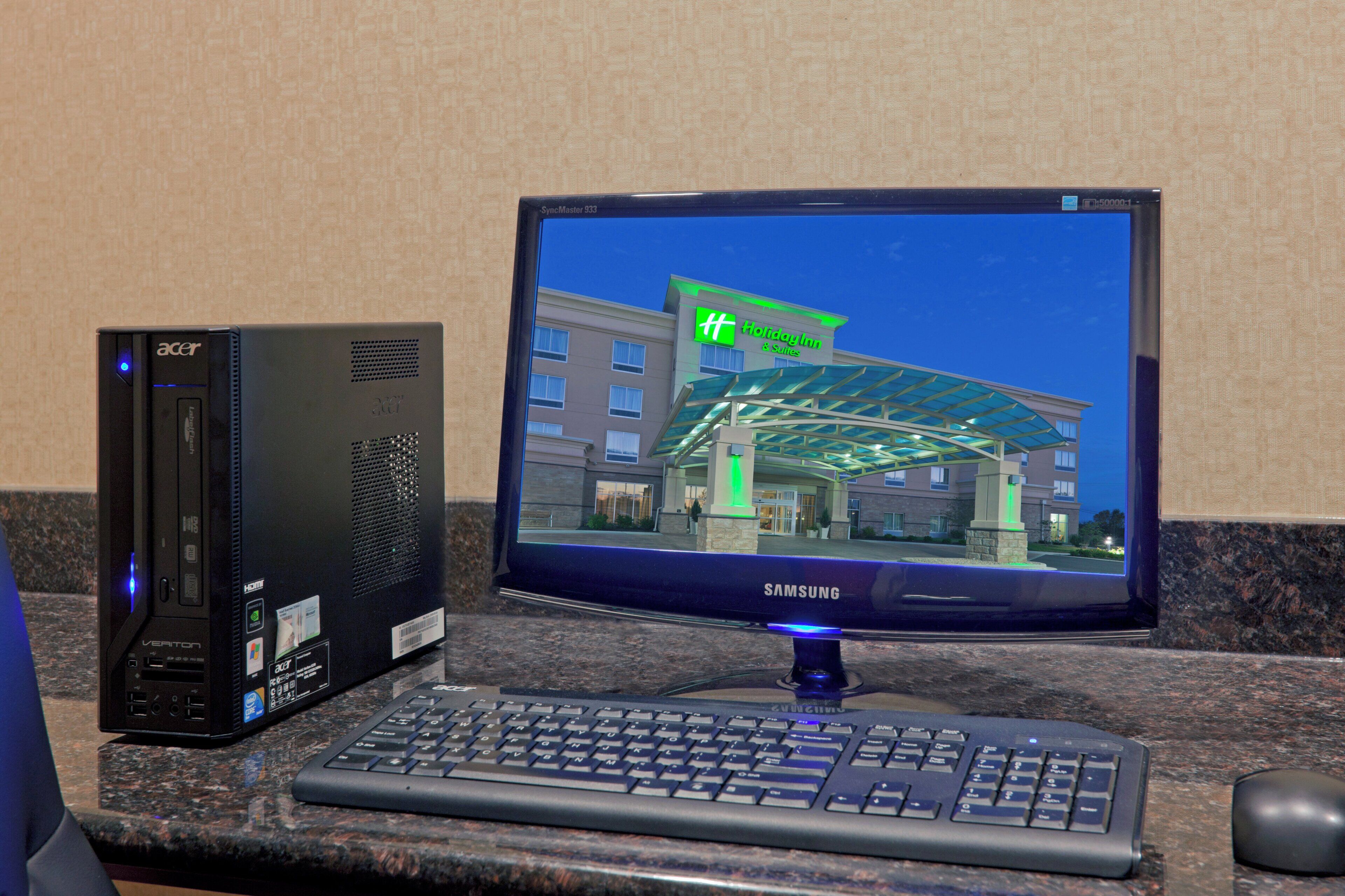 Una computadora con monitor mostrando el letrero de un hotel, teclado y ratón sobre una encimera de granito.