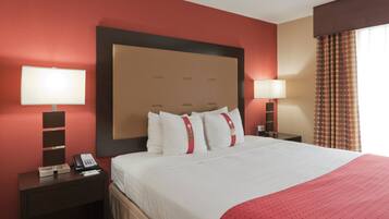 A hotel room with a large bed, two bedside tables, a telephone, and a lamp on each side.