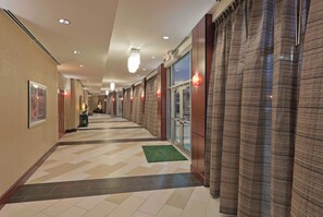 A hotel corridor with a patterned floor, recessed lighting, and a green carpet. - Holiday Inn Hotel & Suites Lima by IHG (Lima)