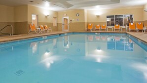 A large indoor swimming pool with clear water, surrounded by orange lounge chairs and a clock on the wall. - Holiday Inn Hotel & Suites Lima by IHG (Lima)
