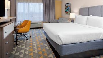 A hotel room with a bed, a desk, a chair, and a window with curtains.