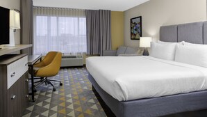 A hotel room with a large bed, a desk with a chair, a window with curtains, and a painting on the wall. - Holiday Inn Hotel & Suites Lima by IHG (Lima)