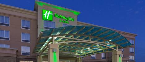 Ein Holiday Inn & Suites Gebäude mit einer Glaskonstruktion als Hauseingang und zahlreichen Fenstern.
