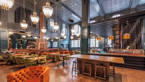 Un restaurante espacioso con techos altos, candelabros y una zona de bar.