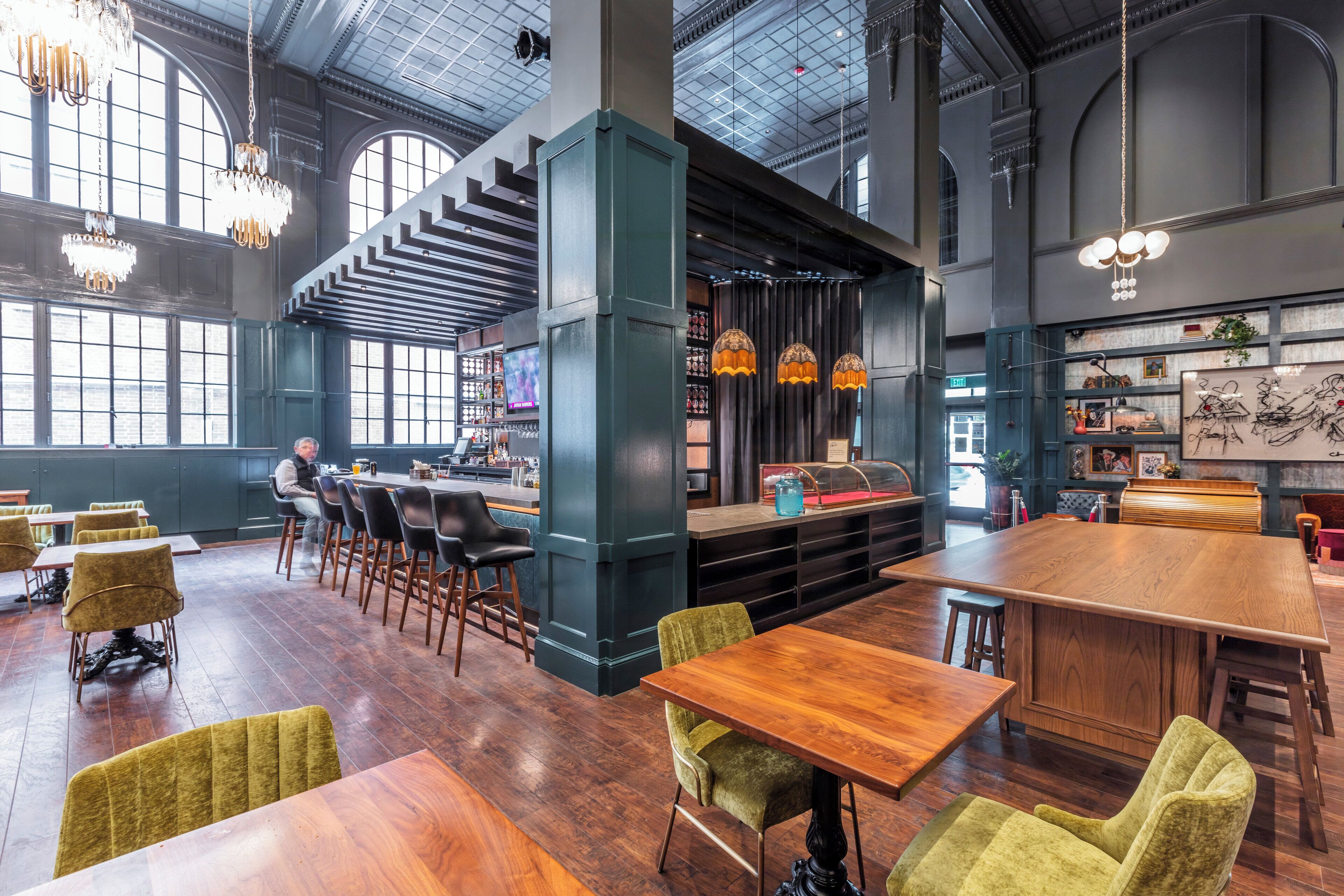 Un restaurant spacieux avec de hauts plafonds, des tables et des chaises en bois, et un coin bar.