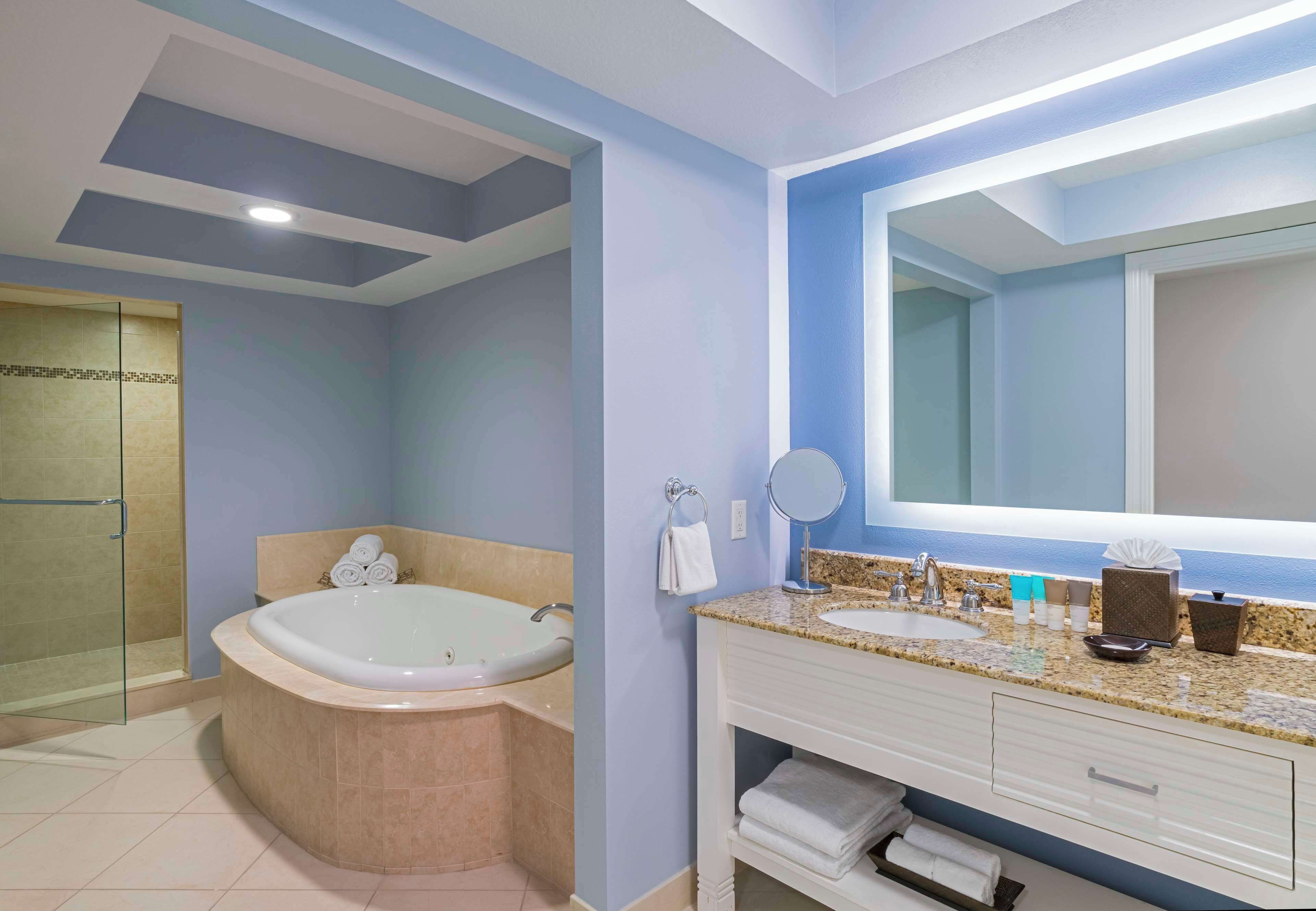 Un baño moderno con una bañera grande, un tocador con lavabo y un espejo amplio.