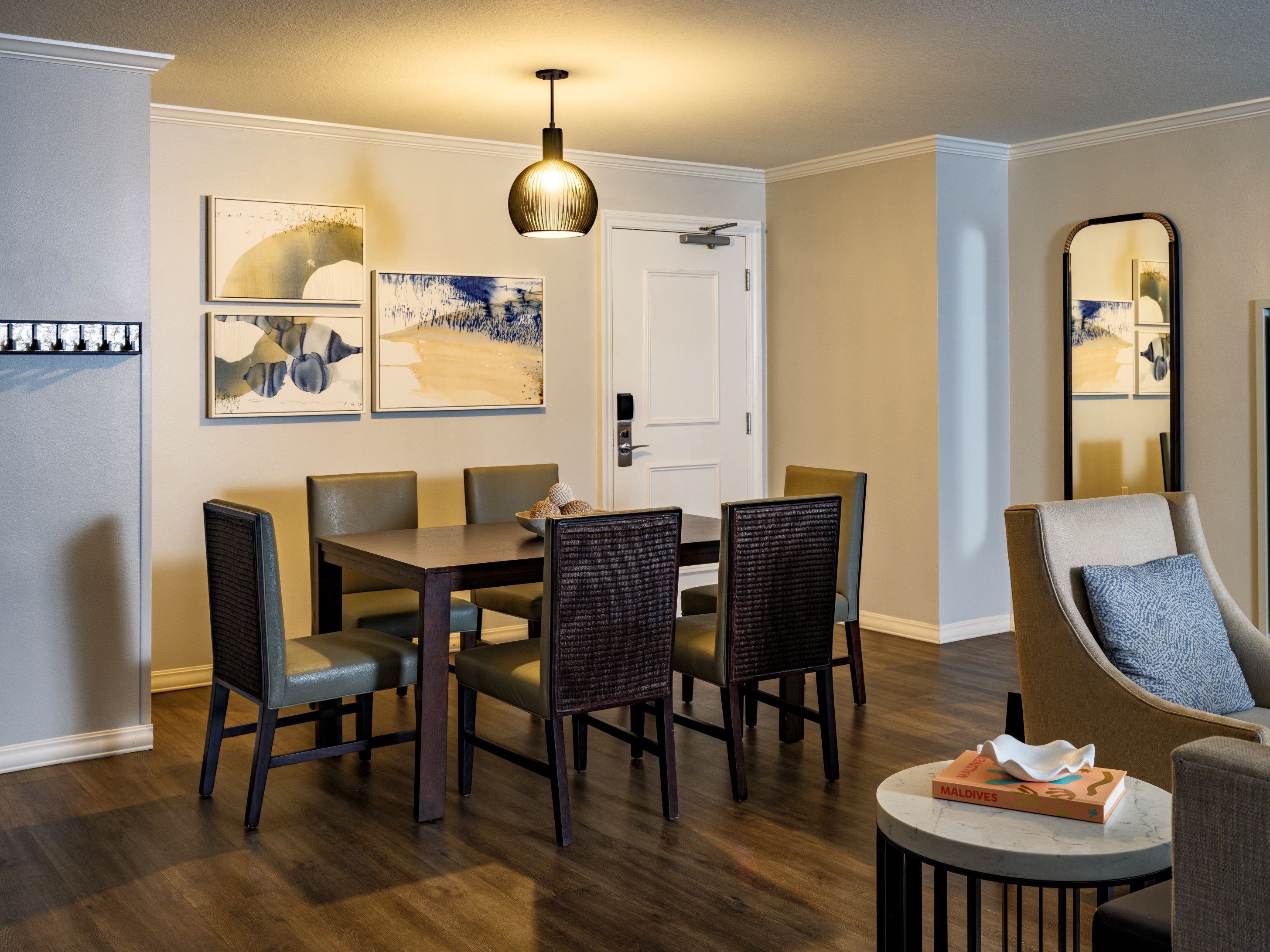 A dining area with a table, chairs, and a hanging light fixture.