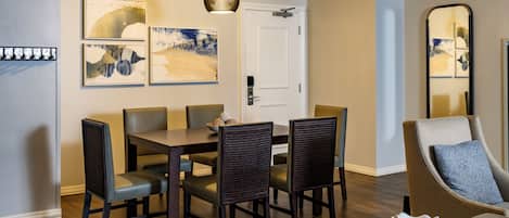 A dining area with a table, chairs, and a hanging light fixture.