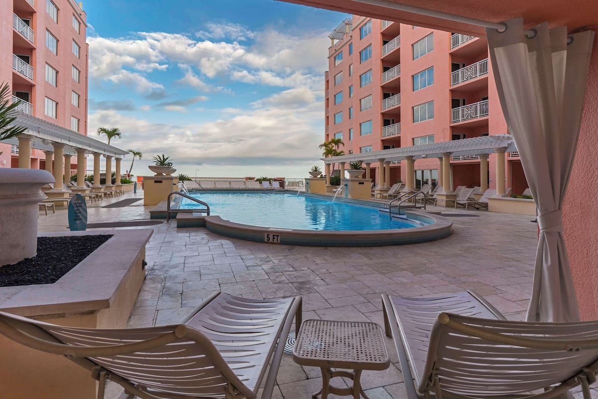 A hotel pool area with lounge chairs and a small pool.