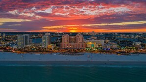 A coastal cityscape at sunset with a beach in the foreground and high-rise buildings in the background. - Hyatt Regency Clearwater Beach Resort and Suites (Clearwater Beach)