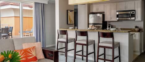 Una habitación de hotel moderna con zona de estar, cocina y balcón.