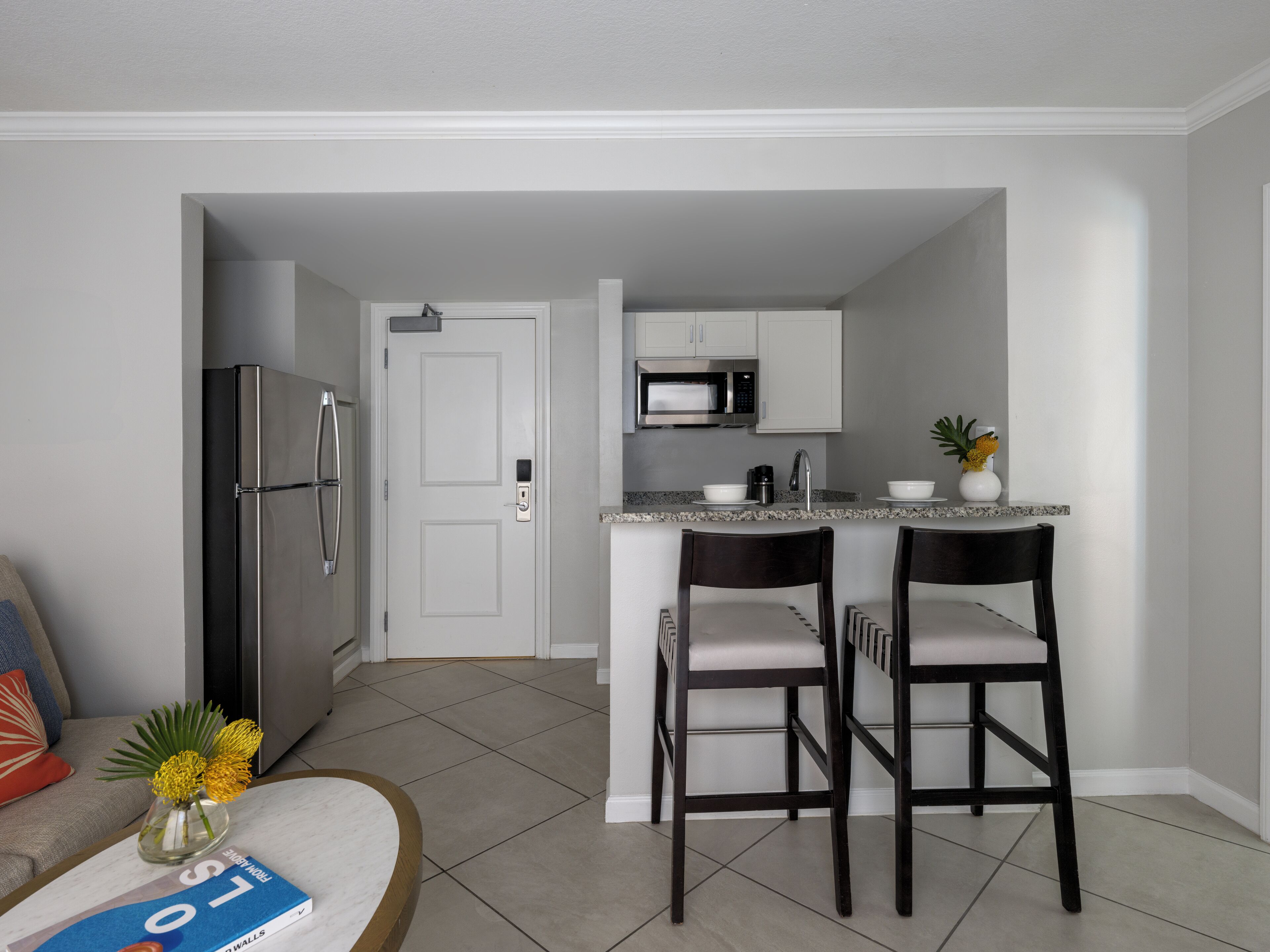 A compact kitchen with a refrigerator, microwave, and a small island with bar stools.