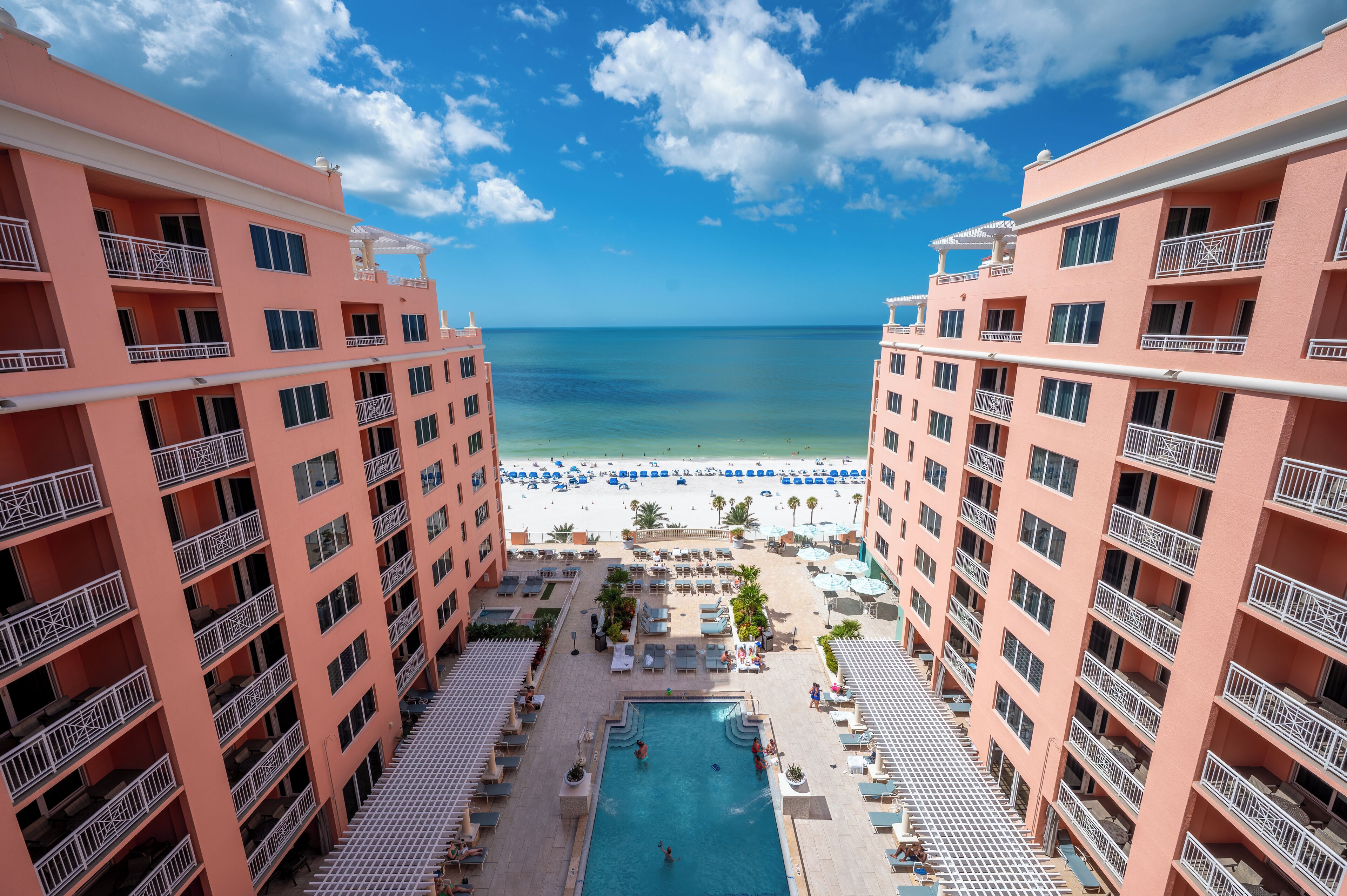 A hotel with a pool, beach view, and multiple balconies.
