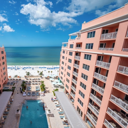 A hotel with a pool, beach view, and multiple balconies.