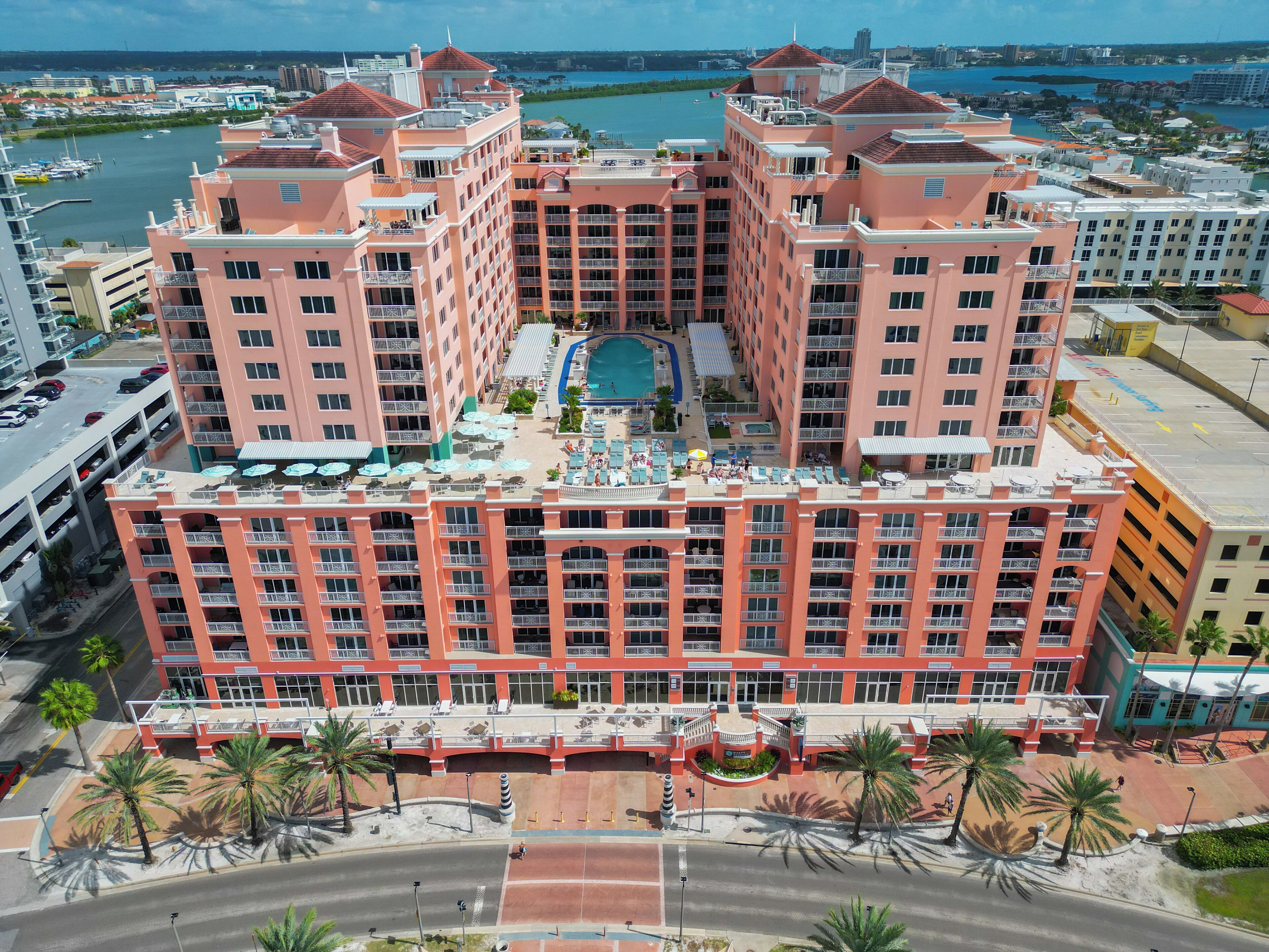 A multi-story hotel with a central courtyard, balconies, and a pool.