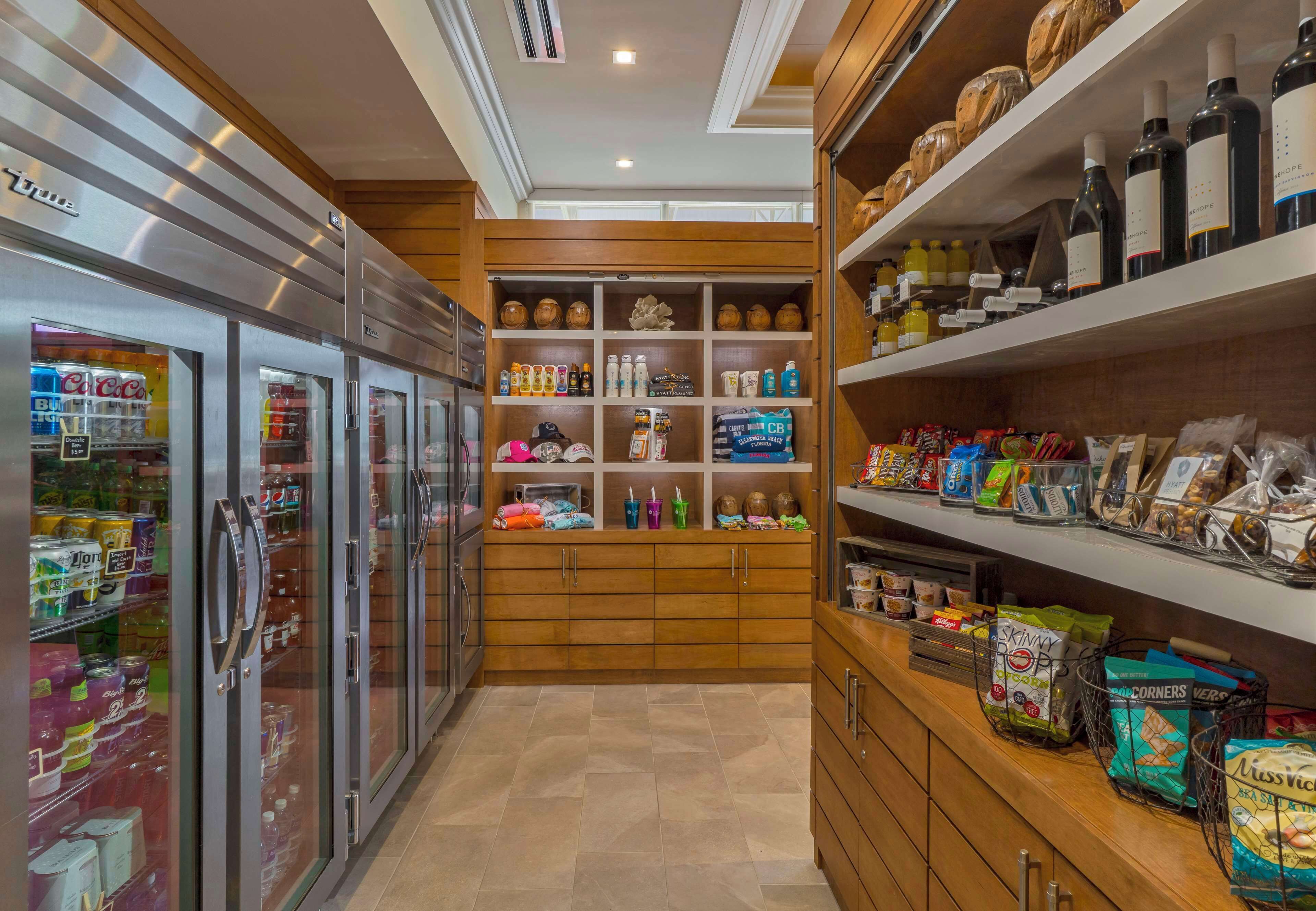 A well-stocked kitchenette with a refrigerator, shelves with beverages, snacks, and a coffee machine.