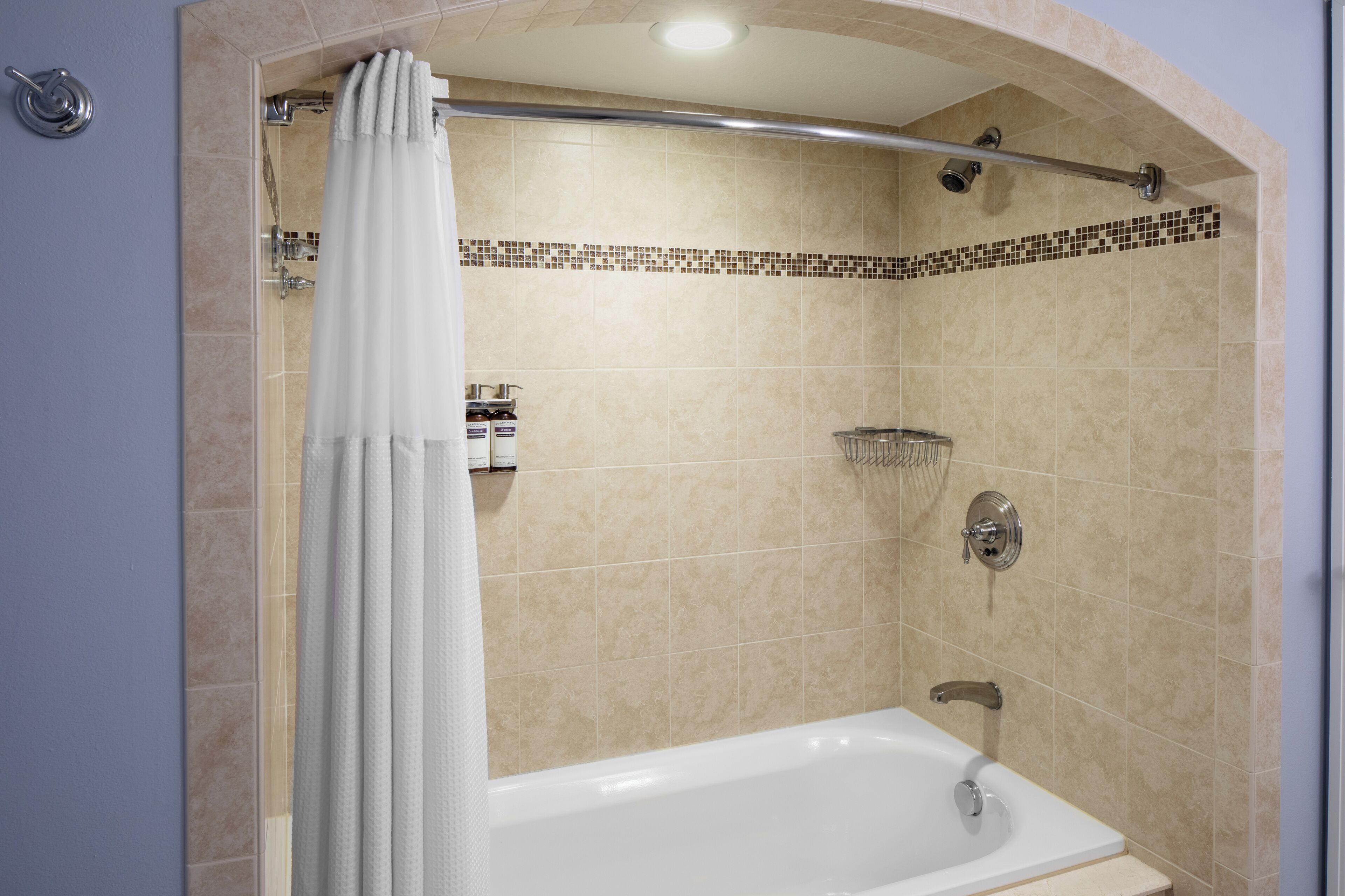 A modern bathroom with a bathtub, shower, and tiled walls.
